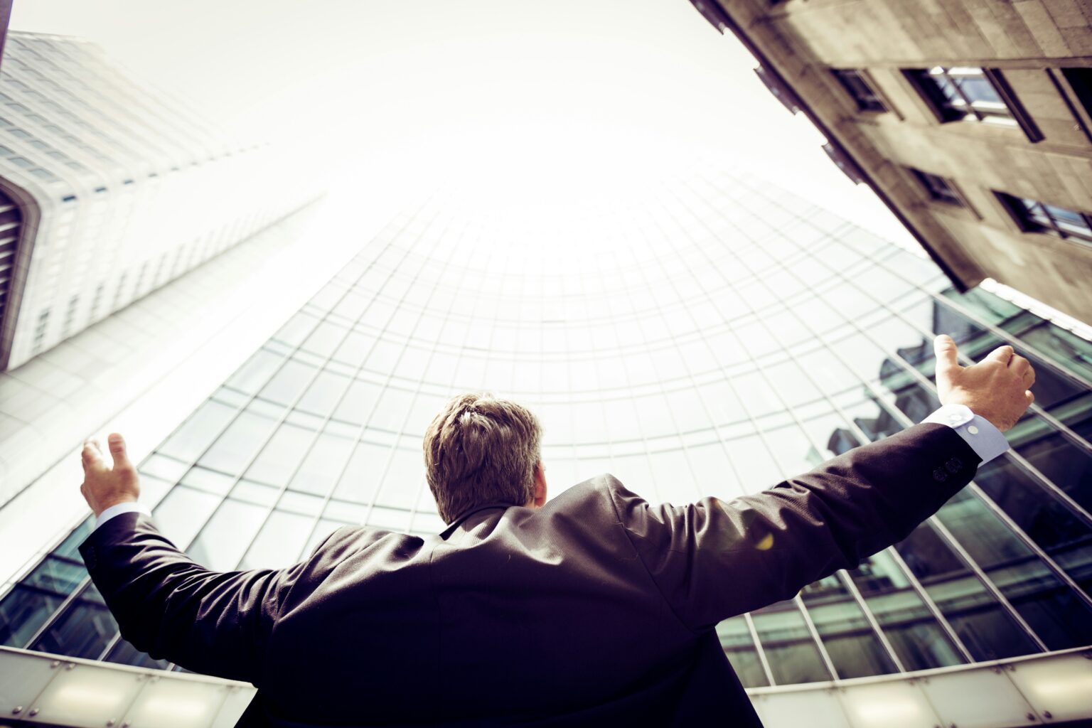 Business professional looking up at office buildings